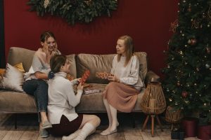 Tres chicas sentadas en un sofá abriendo regalos