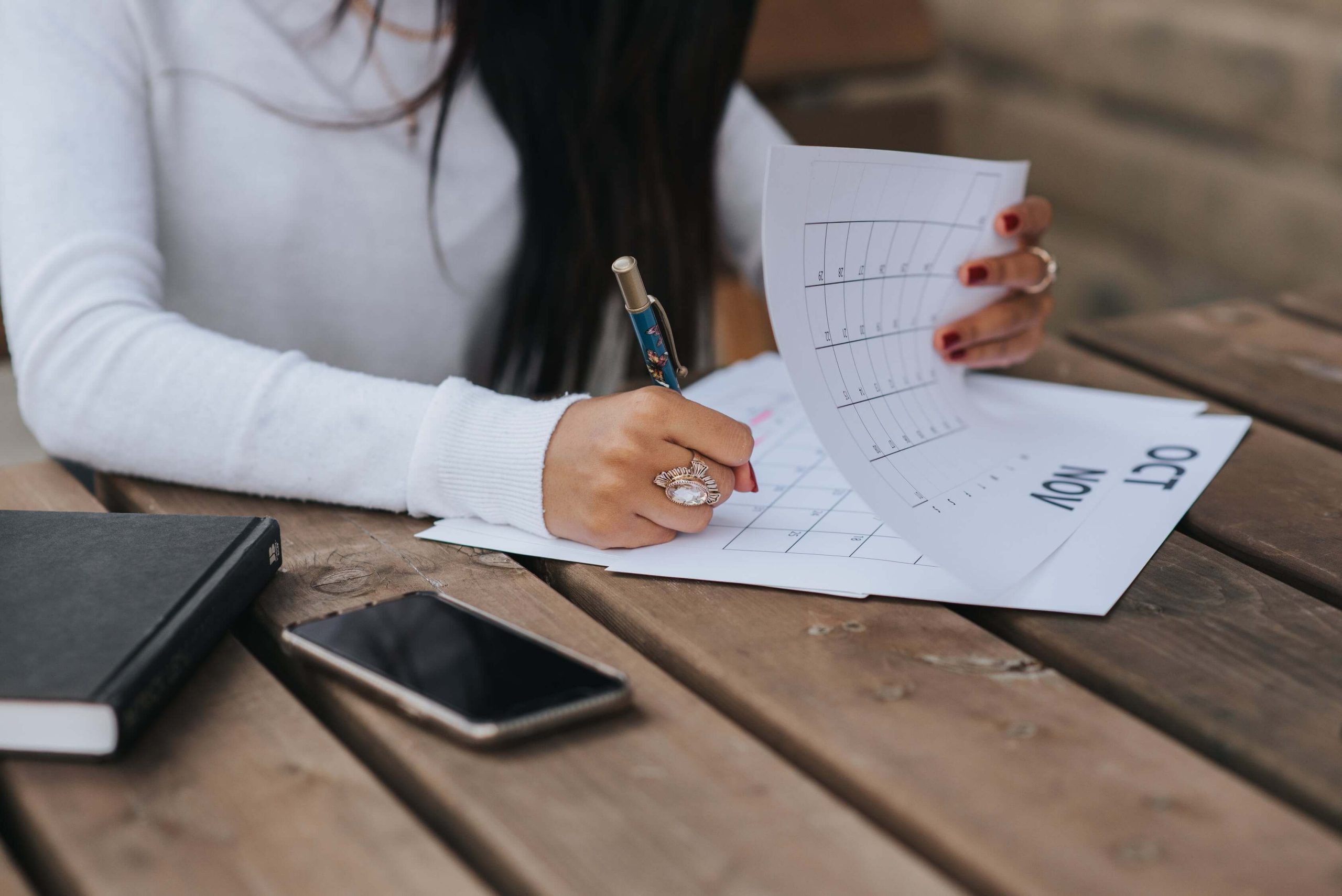 Chica sentada escribiendo apoyada en una mesa propósitos de Año Nuevo